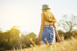 Shot of a young woman on a tree stump out in the countryside.