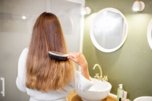 woman combing her hair in bathroom