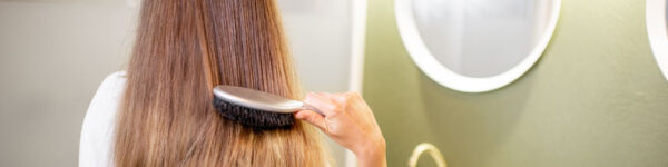 woman combing her hair in bathroom