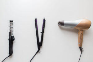 hair dryer, hair straightener, and hair curler on a table